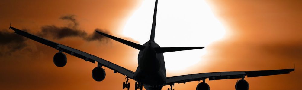 Dramatic silhouette of an airplane flying against a vibrant sunset sky.