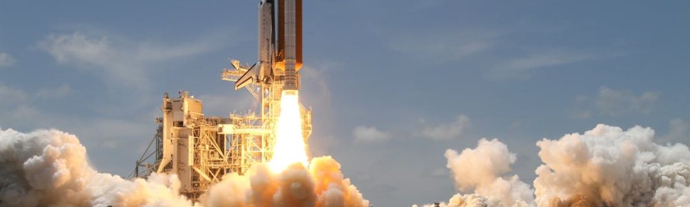 A NASA space shuttle launches with fiery liftoff, ascending into the sky amid plumes of smoke.