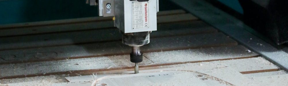 Close-up of a CNC milling machine operating in a workshop setting, cutting patterns into wood.