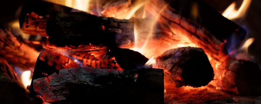 A close-up of a crackling bonfire with vibrant flames and glowing embers.