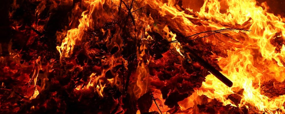 Close-up view of a large, intense bonfire with vibrant flames and burning firewood.