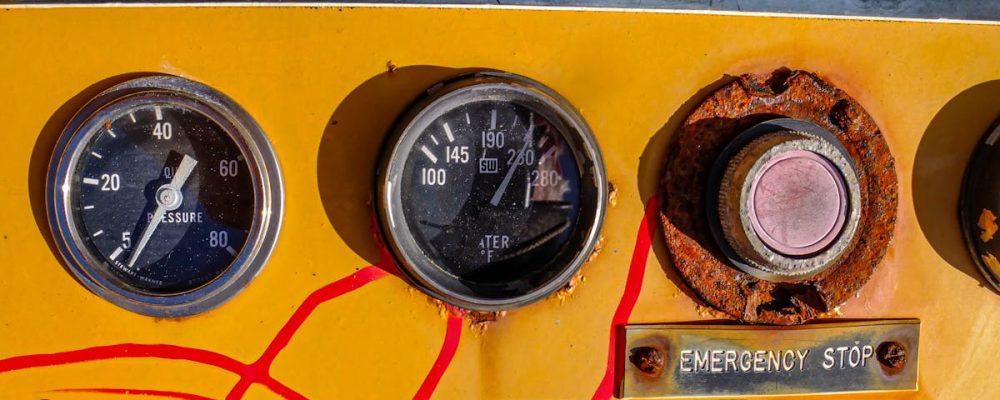 Close-up of a vintage control panel featuring gauges, buttons, and warning labels in a mechanical setting.