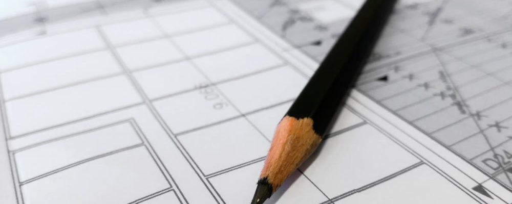 Detailed image of a black pencil resting on architectural blueprints, ideal for design and planning themes.