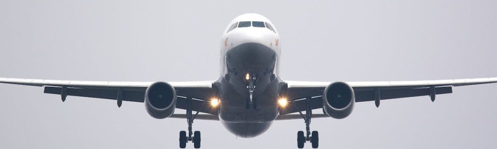 A commercial airliner captured head-on, preparing to land against a cloudy sky.