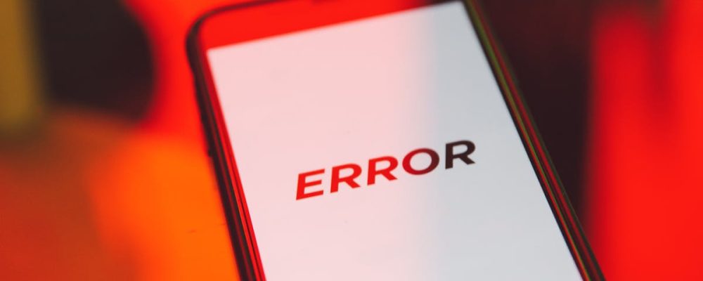 A close-up view of a smartphone showing an error message against a vibrant red background, symbolizing tech issues.