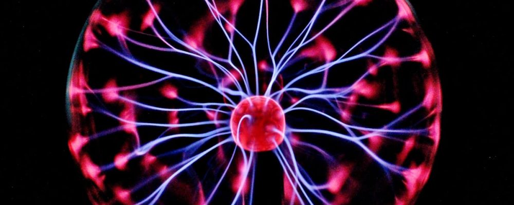 Close-up of a plasma globe with vibrant neon sparks against a dark background.