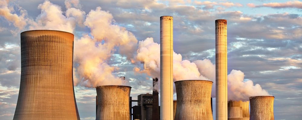 View of a power plant with smoke emissions under a cloudy sky, depicting industrial energy production.