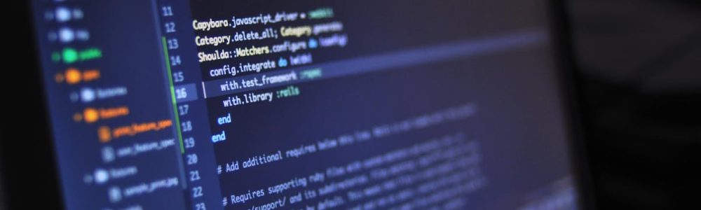 Close-up of a computer screen displaying programming code in a dark environment.