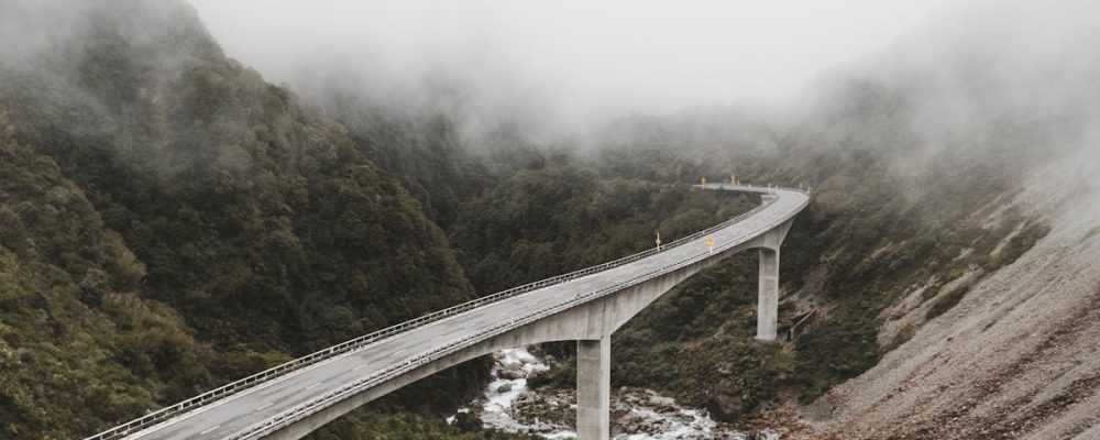 Scenic view of a bridge over a river in a foggy mountain landscape, capturing nature's beauty.