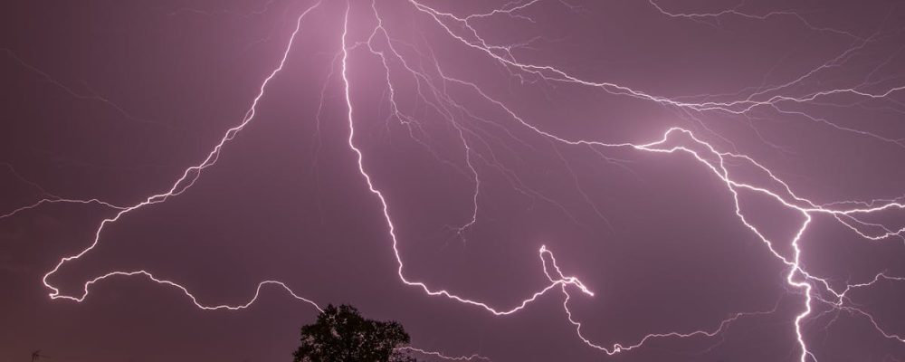 A captivating lightning storm illuminating the night sky above city rooftops.