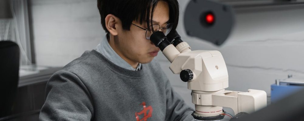 A man using a microscope for scientific research in a laboratory setting.