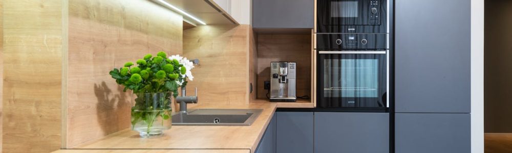Creative design of kitchen with flowers in vase on table against coffeemaker and oven built in cupboard at home