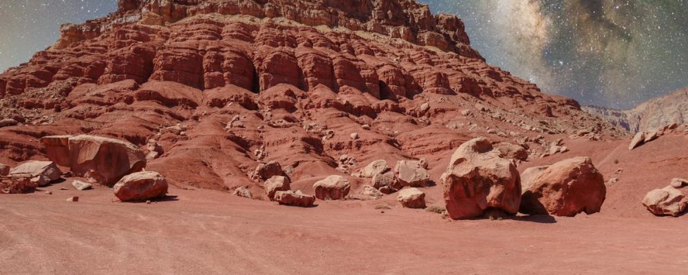 Stunning red rock formations under the Milky Way, resembling a Martian terrain.