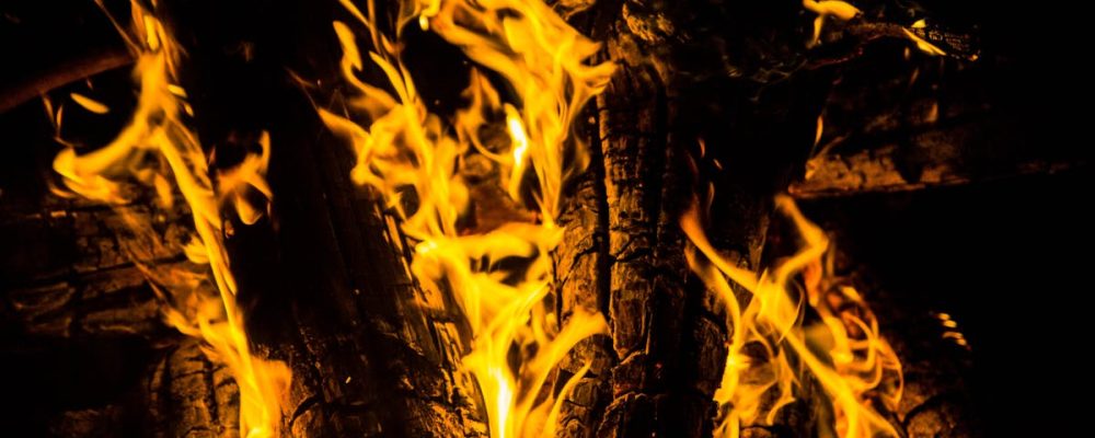 Close-up of a blazing campfire with intense flames illuminating a dark night.