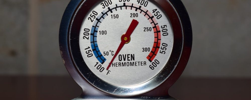 Close-up of a metallic oven thermometer showing temperature in Celsius and Fahrenheit.