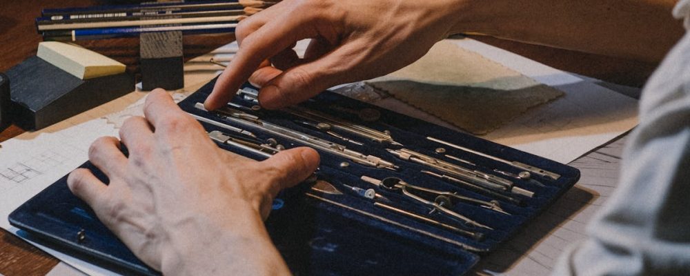 Adult male focused on technical drawing using drafting tools on a desk indoors.